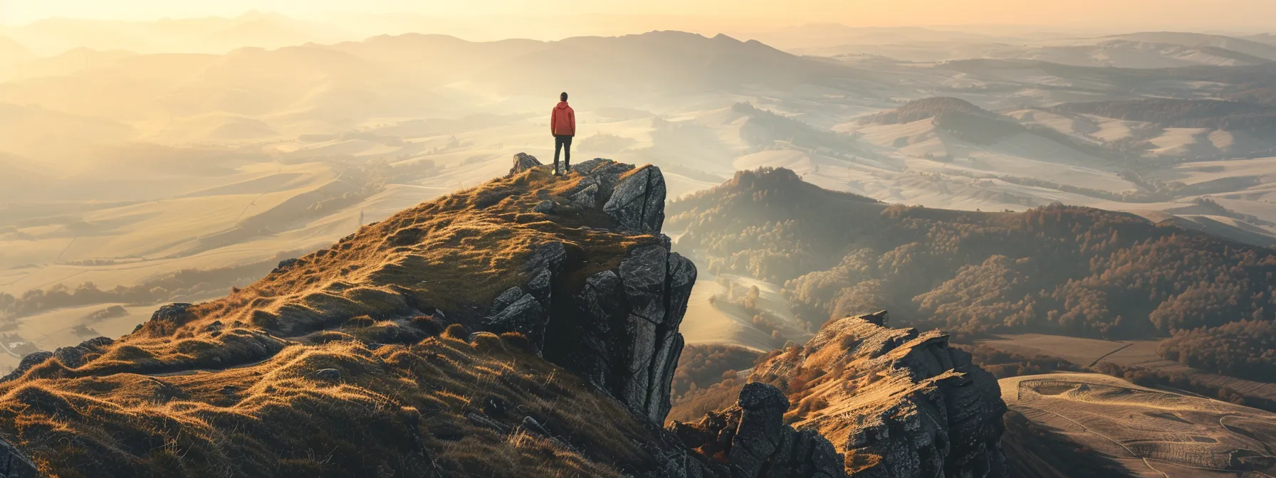 a person standing on top of a mountain, looking out at a vast and open landscape.