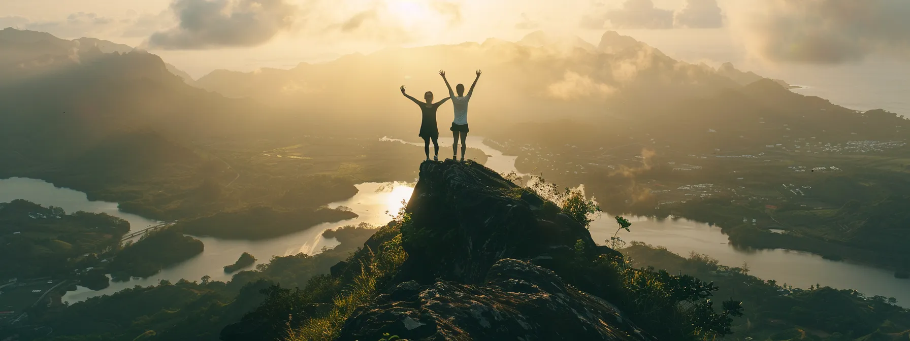 a person standing on top of a mountain triumphantly raising their arms in victory.