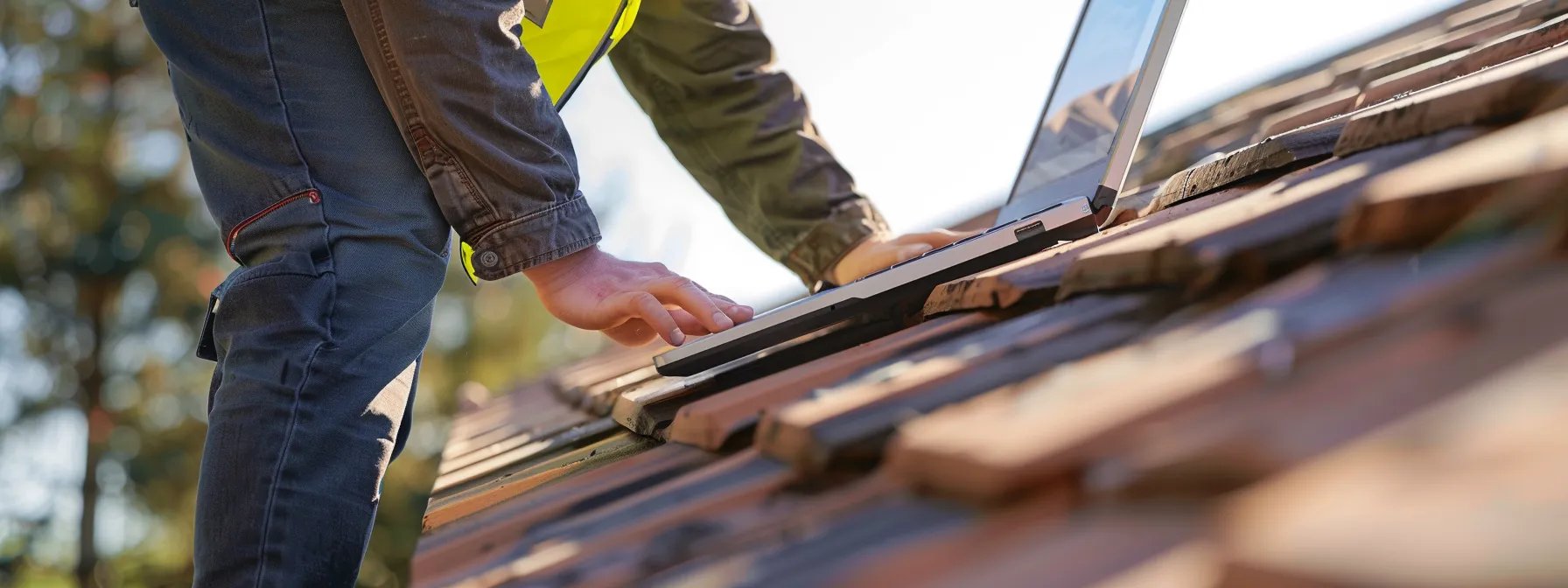 a roofer examining a google my business listing on a laptop while holding positive customer reviews in hand.